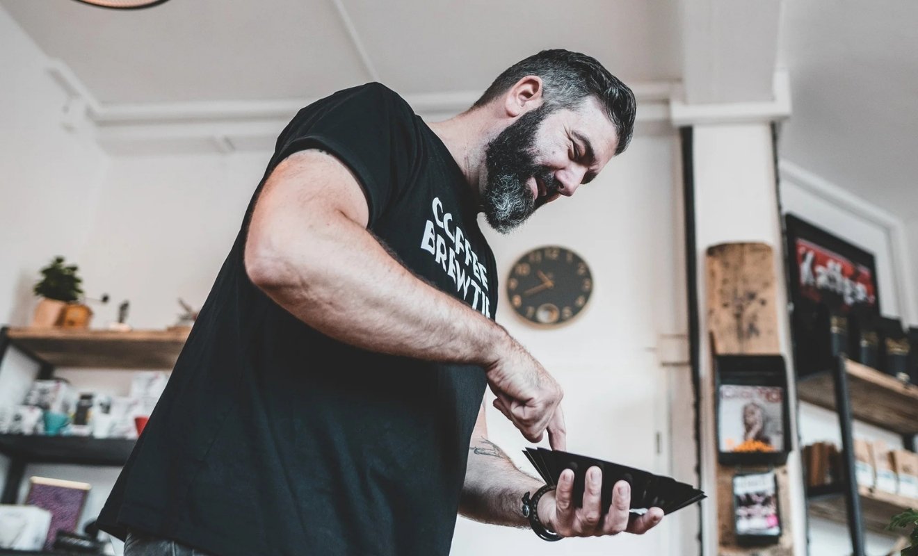 Mann zeigt auf Schale mit Kaffeebohnen bei Kaffeeseminar