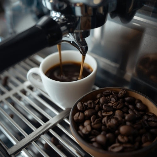 Kaffeebohnen neben Tasse in Kaffeemaschine